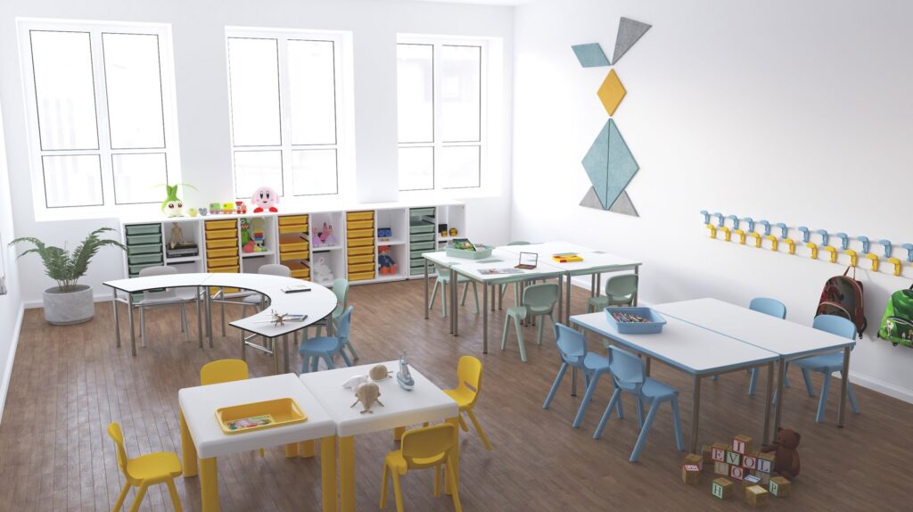 Une salle de classe moderne et lumineuse dans une École numérique avec de grandes fenêtres, des tables et des chaises colorées, des étagères de jouets et de livres, des œuvres d'art murales et des crochets avec des tasses le long du mur. Le matériel pédagogique est bien rangé dans la salle.