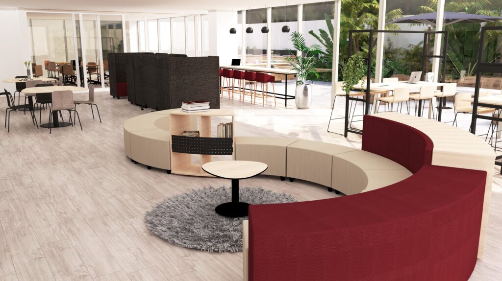 Bureau ouvert moderne avec des sièges courbes beiges et rouges, un tapis circulaire, des petites tables et divers espaces de travail. De grandes fenêtres laissent entrer la lumière naturelle et laissent apparaître des plantes vertes à l'extérieur, ce qui est idéal pour les échanges dans les espaces informels.