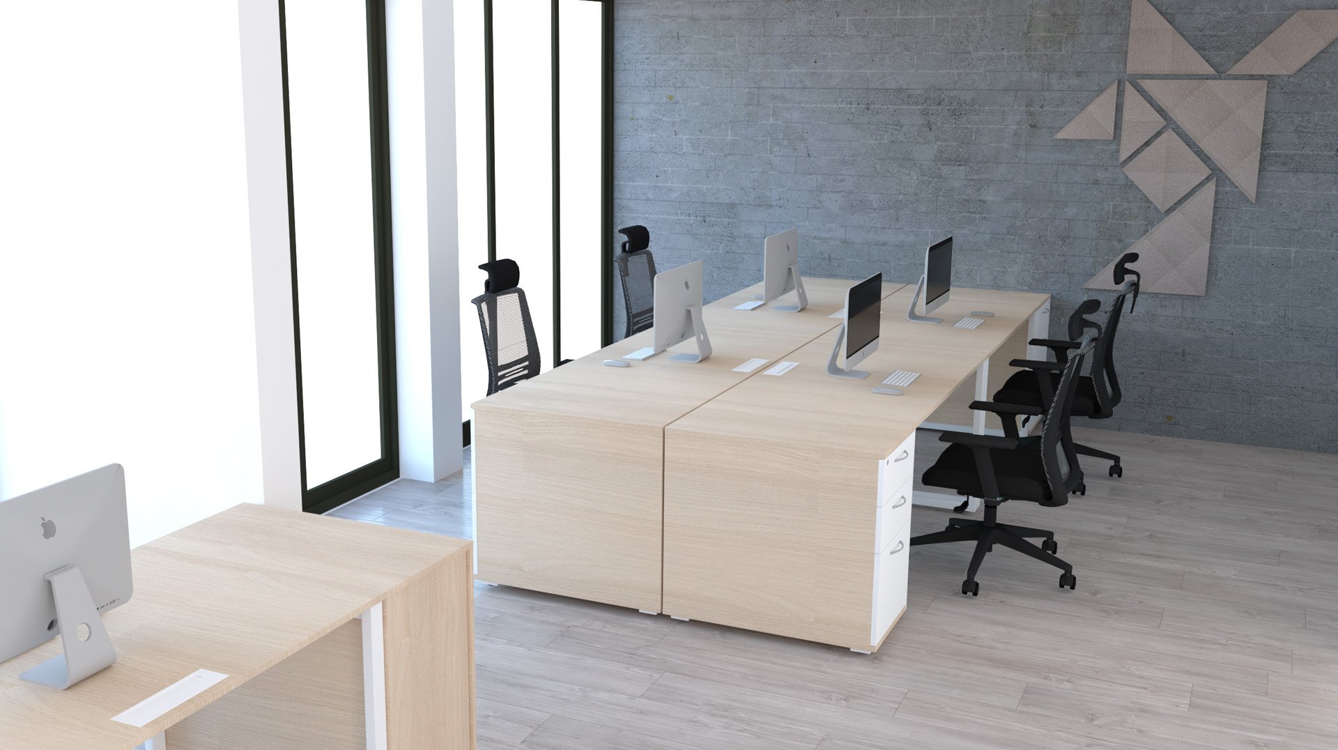 Un bureau moderne avec des bureaux en bois clair, des chaises ergonomiques noires et plusieurs ordinateurs de bureau. De grandes fenêtres laissent entrer la lumière naturelle et des œuvres d'art géométriques décorent un mur gris. L'espace semble propre et organisé.