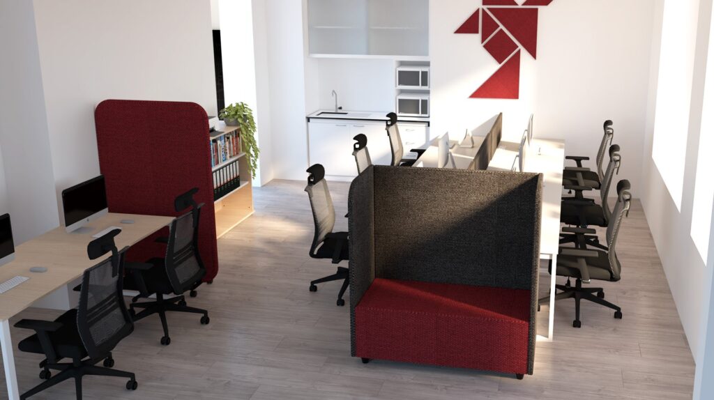 Espace de bureau moderne avec des bureaux, des chaises de bureau noires, des cabines privées avec un revêtement rouge et gris, des étagères ouvertes, une petite kitchenette et des œuvres d'art murales abstraites rouges. Les planchers en bois clair et les grandes fenêtres créent une atmosphère lumineuse.