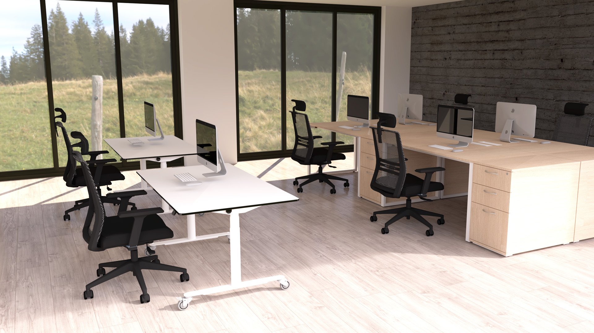 Bureau moderne avec de grandes fenêtres montrant un paysage extérieur herbeux, plusieurs bureaux avec des chaises noires, des ordinateurs de bureau et un sol en bois clair. La pièce est lumineuse et peu décorée.