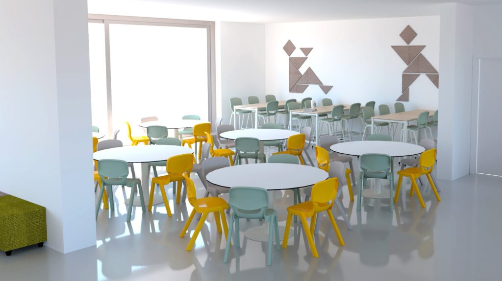 Une cafétéria moderne et lumineuse avec des tables rondes entourées de chaises jaunes et vertes. Des tables hautes avec des tabourets se trouvent près du mur du fond, qui est décoré d'art géométrique. De grandes fenêtres laissent entrer la lumière naturelle.