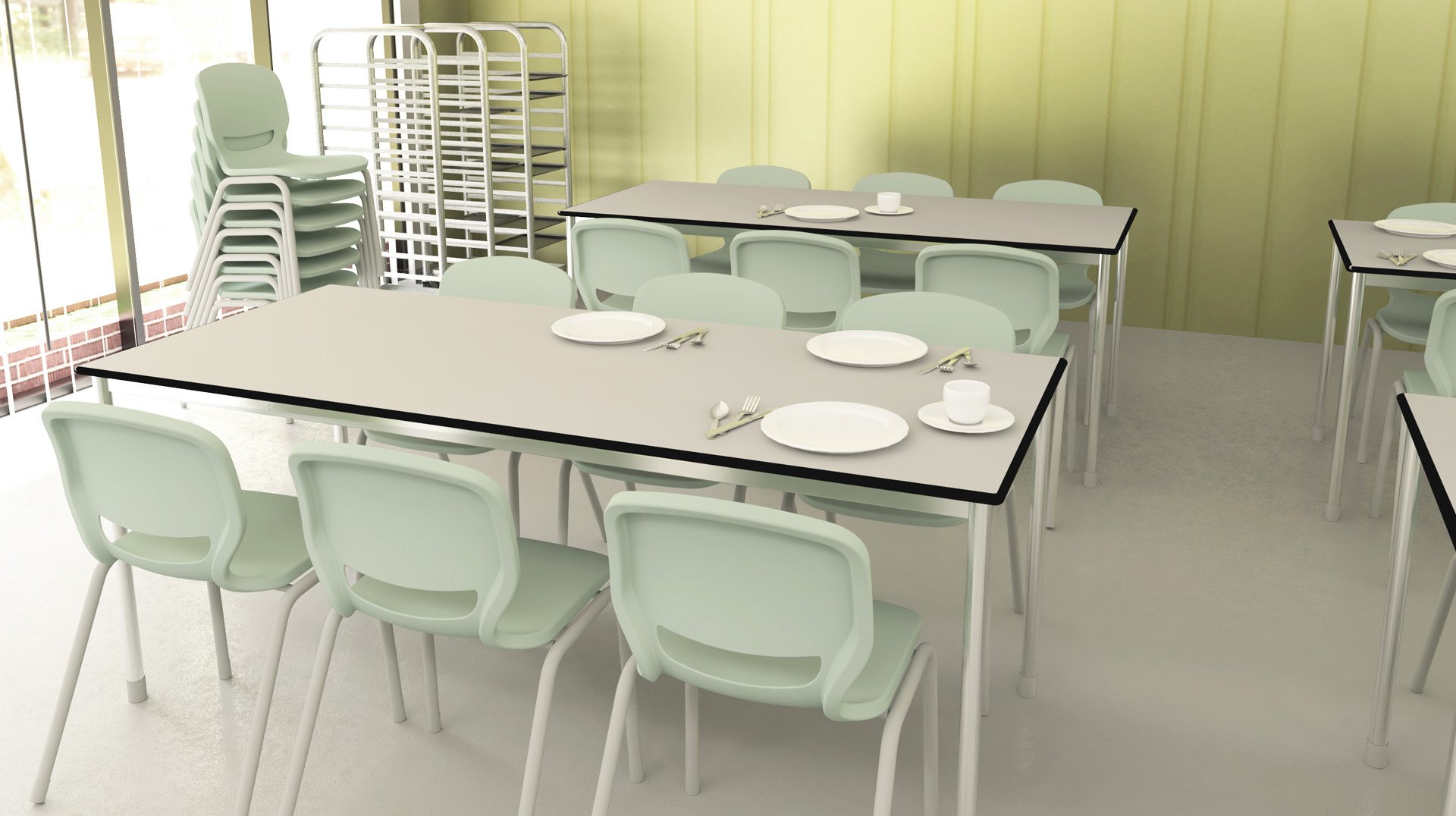 Une cafétéria vide et propre, avec des chaises empilées, des tables garnies d'assiettes, de tasses et de couverts, et un porte-plateaux contre un mur jaune. La lumière naturelle pénètre par de grandes fenêtres.