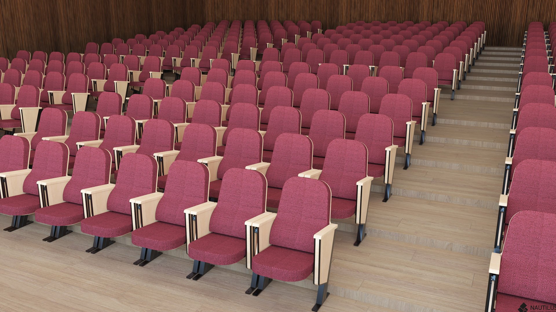 Des rangées de sièges rouges vides de théâtre ou d'amphithéâtre, avec des accoudoirs en bois et un sol en gradins, orientés vers l'avant de la salle. Les murs sont recouverts de panneaux de bois.