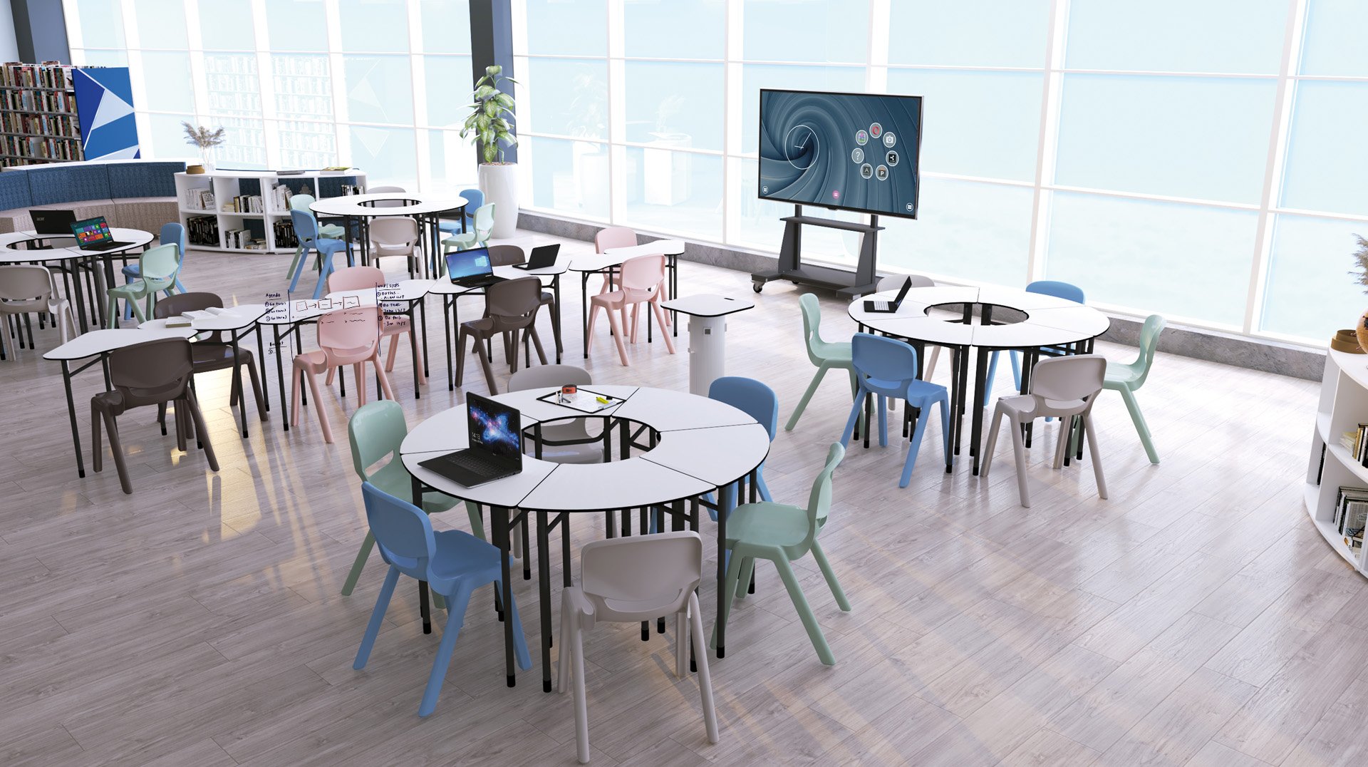 Une salle de classe moderne et lumineuse avec des tables rondes, des chaises aux couleurs pastel, des ordinateurs portables, des livres, un grand écran et des étagères rappelant une bibliothèque. De grandes fenêtres laissent entrer la lumière naturelle, rendant l'espace organisé à la fois accueillant et inspirant.