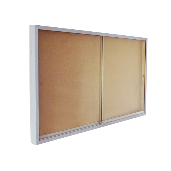 La Vitrine en acier est un tableau d'affichage rectangulaire en liège avec un cadre en métal argenté et deux portes coulissantes en verre, présenté de biais sur un fond blanc.