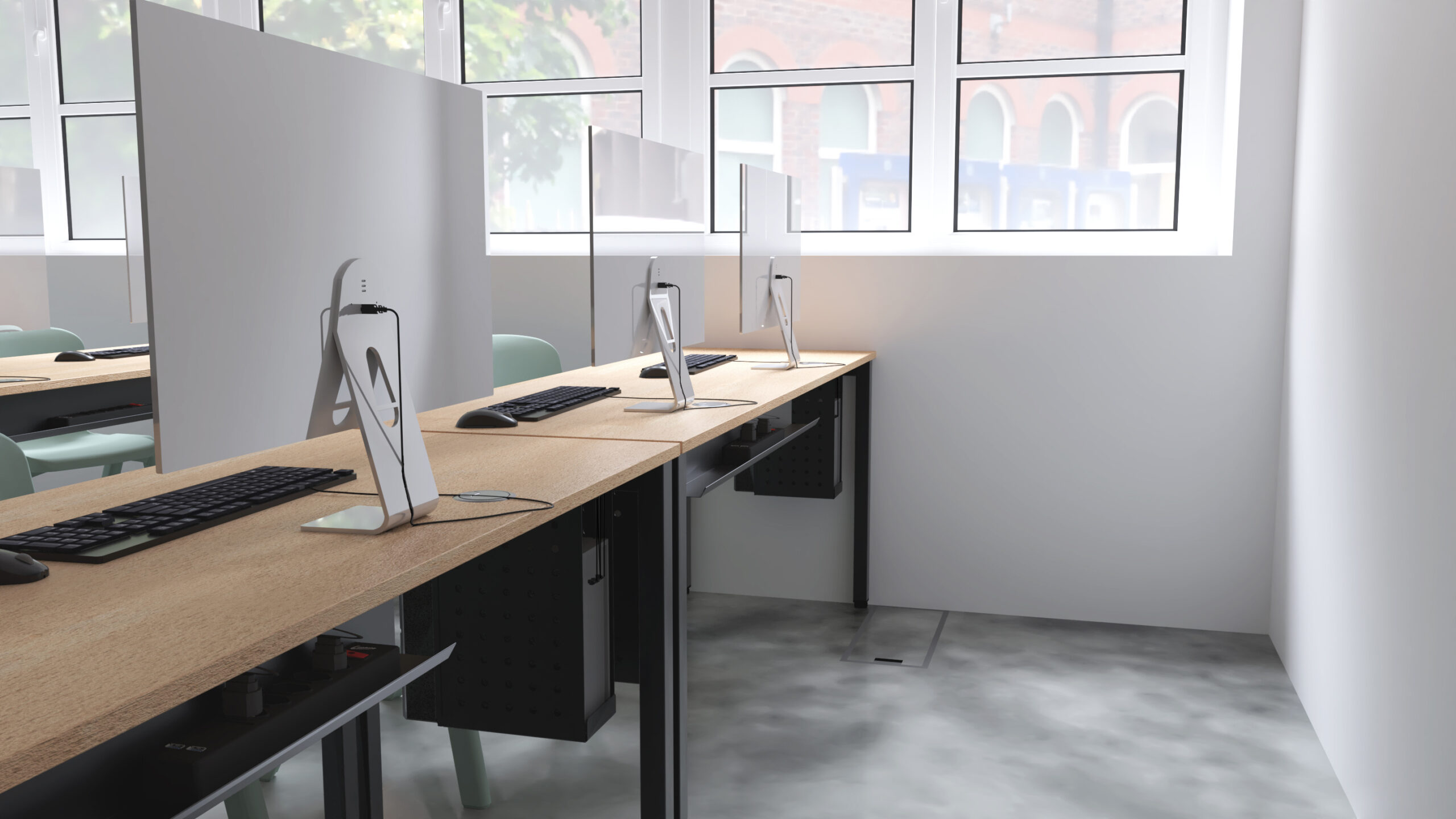 Une rangée de postes de travail modernes équipés d'ordinateurs de bureau, de claviers et de chaises, séparés par des cloisons dans une pièce lumineuse avec de grandes fenêtres laissant entrer la lumière naturelle.