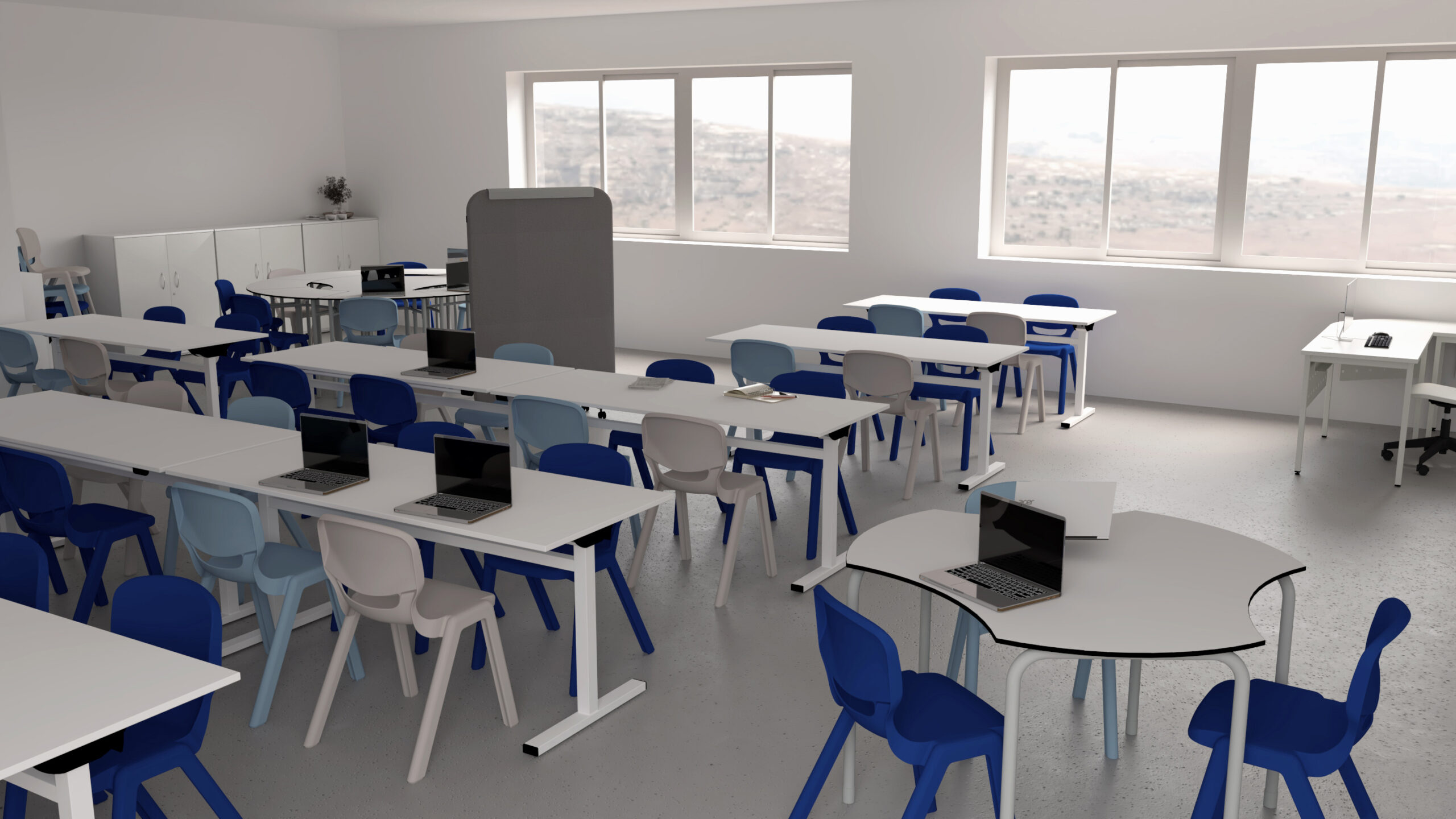 Une salle de classe moderne avec des tables blanches, des chaises bleues et beiges et plusieurs ordinateurs portables sur les bureaux. De grandes fenêtres laissent entrer la lumière naturelle, et des armoires et des ordinateurs se trouvent le long du mur du fond. La salle est spacieuse et organisée.