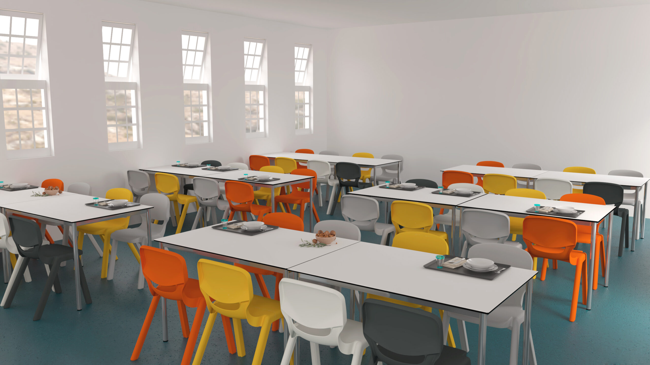 Une cafétéria lumineuse aux murs blancs et aux grandes fenêtres, meublée de tables rectangulaires et de chaises en plastique colorées en jaune, orange et blanc. Sur certaines tables sont disposés des plateaux, des assiettes et des ustensiles.