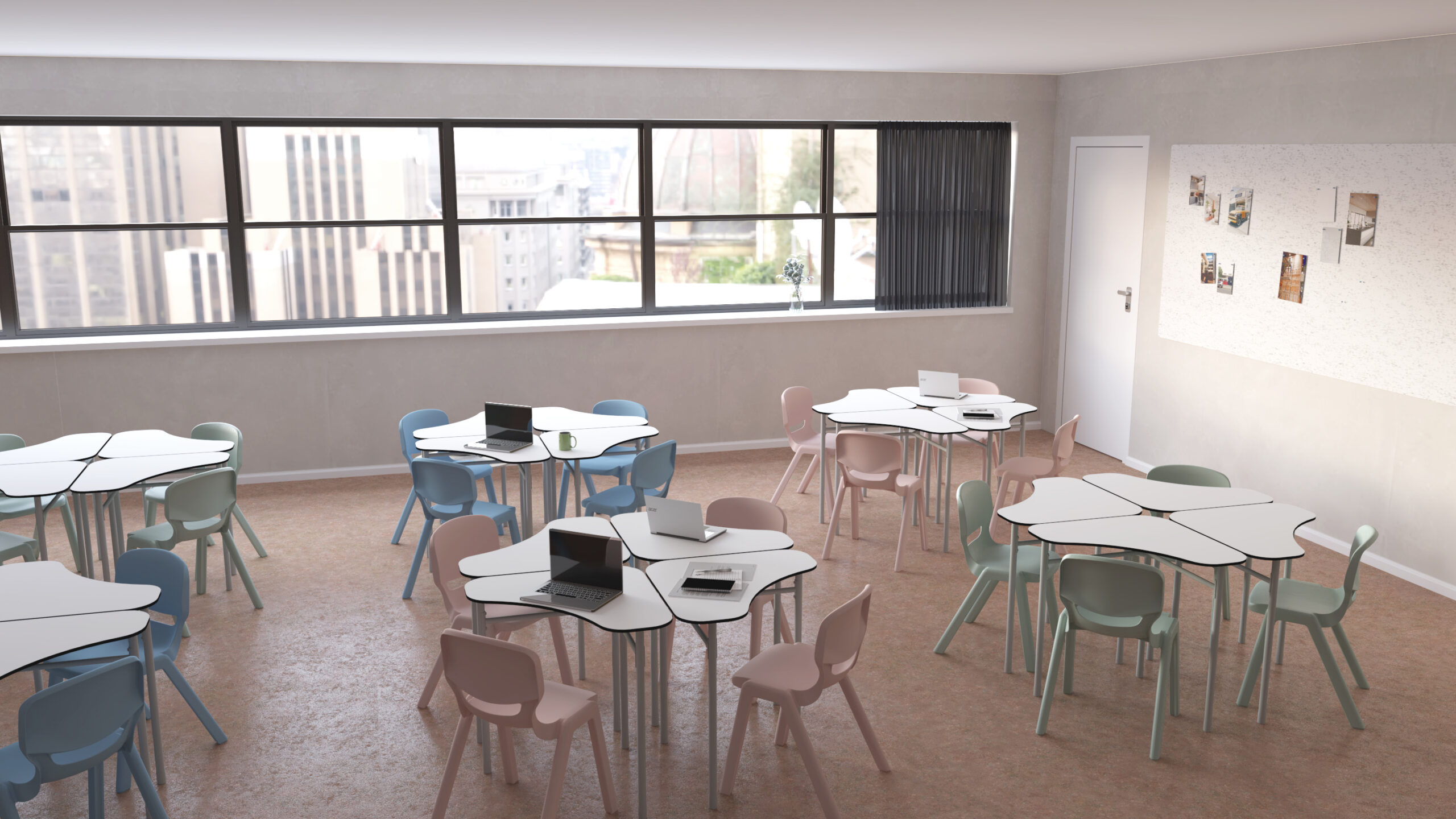 Une salle de classe moderne de l'École numérique avec des tables hexagonales, des chaises aux couleurs pastel et des ordinateurs portables ouverts. De grandes fenêtres offrent une vue sur la ville et un tableau d'affichage avec des photos est accroché au mur près d'une porte fermée.